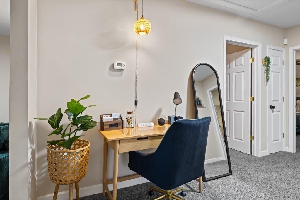A home office with a desk, chair, lamp, and a mirror.
