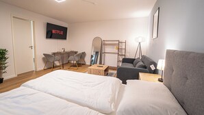 Une chambre d’hôtel moderne, dotée d’un grand lit, d’un bureau, d’une chaise, d’un canapé et d’un téléviseur fixé au mur.