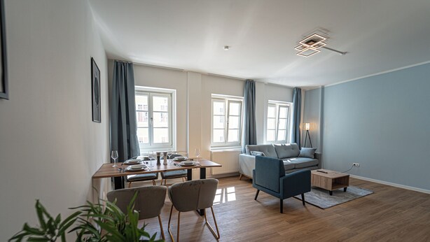 Un grand espace de vie comprenant une table à manger, des chaises, un canapé et une petite table d’appoint.