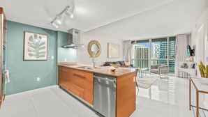 Una cocina moderna con una isla central, un comedor con vistas y una sala de estar con sofá y mesa de centro.
