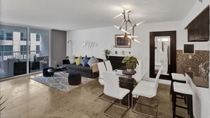 A modern living room with a grey sofa, white chairs, a glass dining table, and a chandelier. - Superb Private unit Perfectly Located In Brickell (Miami)