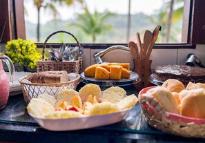 Um buffet de café da manhã com diversos pães, bolos e frutas.