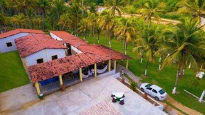 Uma casa com telhado de telhas, uma rede e um carro estacionado em frente.