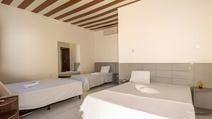 Ein Hotelzimmer mit zwei Einzelbetten, einem kleinen Schreibtisch, einem Stuhl, einem Spiegel und einem Nachttisch.