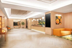 A spacious hotel lobby with a reception desk, seating area, and a large television screen. - Orange Hotel (Shanghai Bund Waibaidu Bridge) (Shanghai)