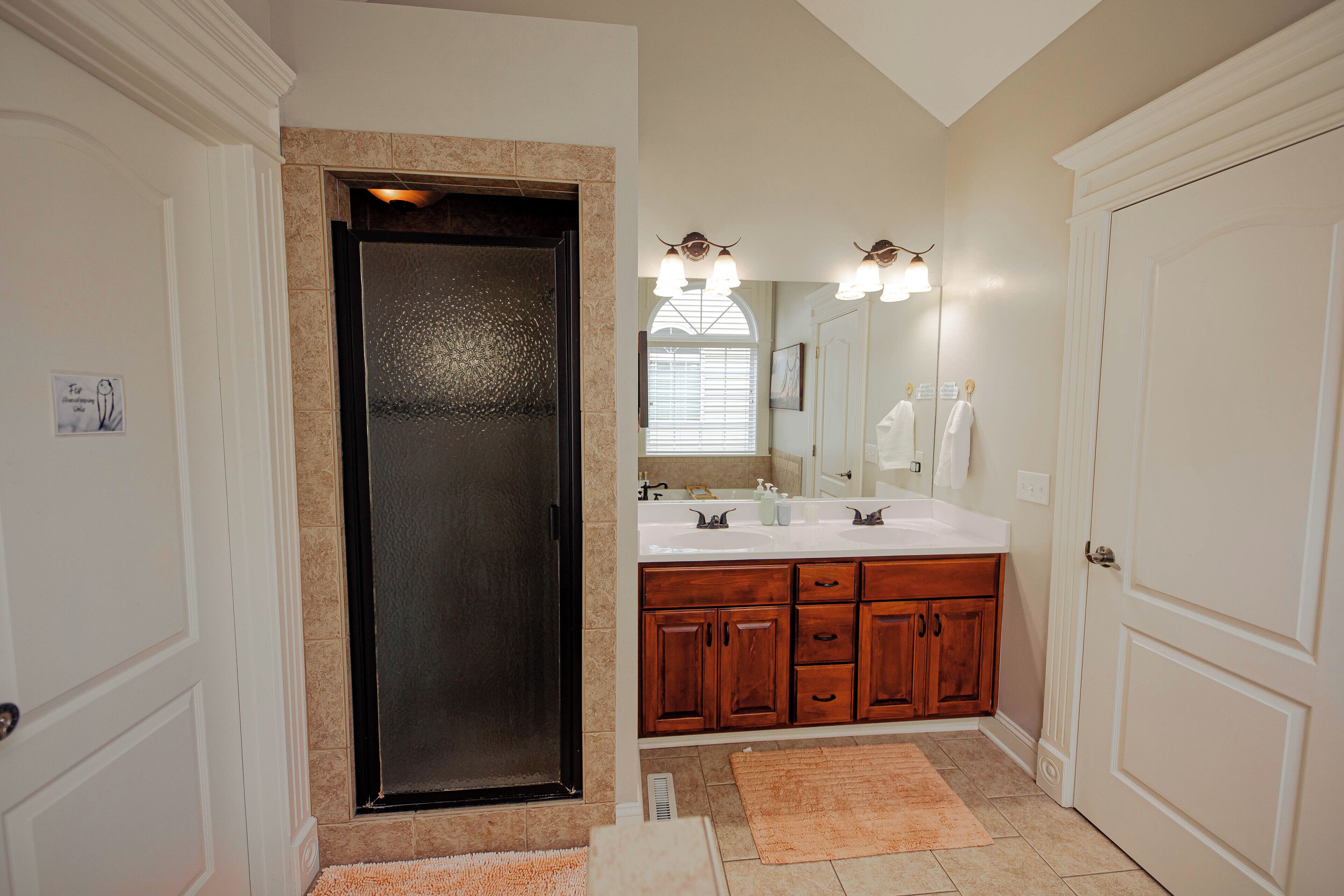 A bathroom with a double sink vanity, a large mirror, and a door with a frosted glass panel.