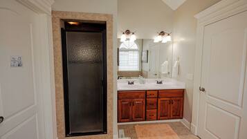 A bathroom with a double sink vanity, a large mirror, and a door with a frosted glass panel.