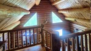 Una cabaña de madera con techo inclinado, una escalera de madera y dos ventanas.