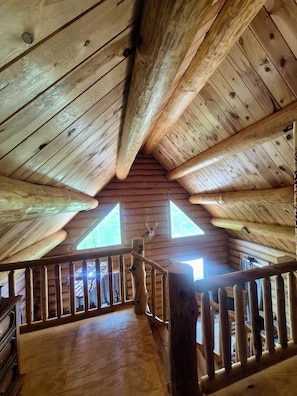 Una cabaña de madera con techo inclinado, una escalera de madera y dos ventanas.