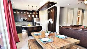 Une cuisine moderne avec des meubles de couleur sombre, des appareils en acier inoxydable et des luminaires suspendus.