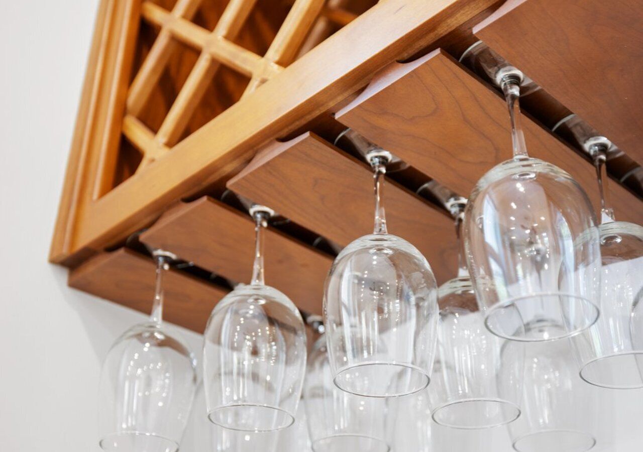 A row of clear wine glasses hanging from a wooden structure.