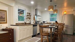 Una cocina moderna con armarios blancos, una mesa de comedor de madera y sillas.