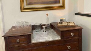 Un aparador de madera con cubierta de mármol, una jarra de cristal y un juego de ajedrez.