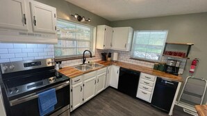 Une cuisine moderne avec des armoires blanches, une cuisinière noire et un plan de travail en bois.