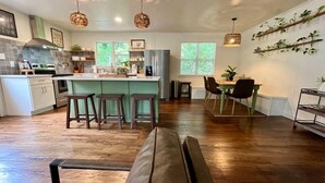 Een moderne keuken met een centraal eiland, houten vloeren en hanglampen.