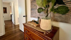 Een hal met een houten dressoir, een potplant en een geweven mand.