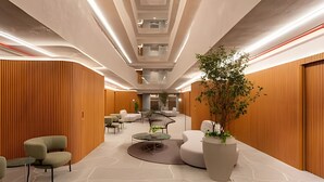 Eine moderne Lobby mit einer gebogenen Lounge, einer großen Kübelpflanze und Holzpaneelen an den Wänden.