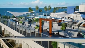 Eine Dachterrasse mit Pool, Liegestühlen und Blick auf das Meer.