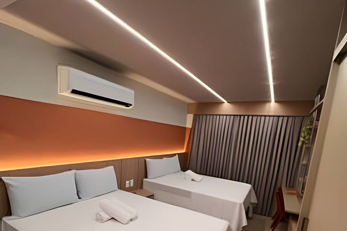 A hotel room with two beds, a modern design, and a small seating area.