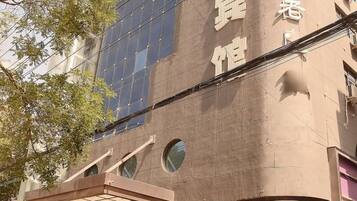 A building with a beige facade, large windows, and a visible solar panel installation.