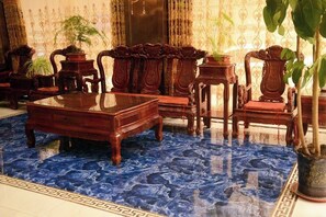 A room with a blue marble floor, wooden furniture, and potted plants. - Dingxi Jingu Hotel (Dingxi)
