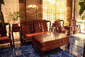 A room with a wooden coffee table, matching chairs, and a patterned floor. - Dingxi Jingu Hotel (Dingxi)