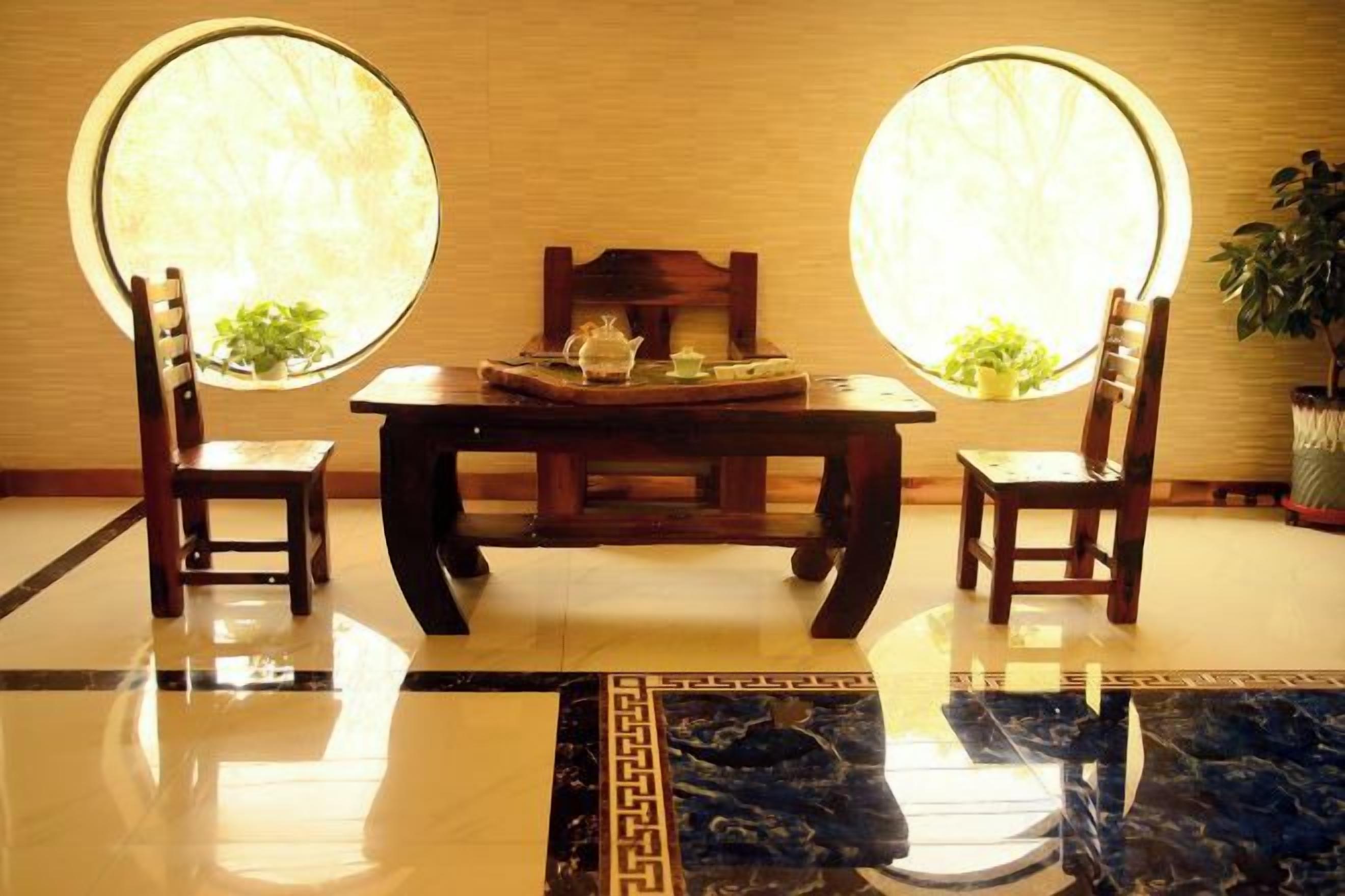 A room with a round table, two chairs, a potted plant, and a window with a view.
