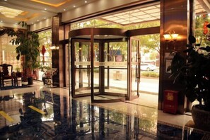 A hotel lobby with a revolving door, a polished marble floor, and potted plants. - Dingxi Jingu Hotel (Dingxi)