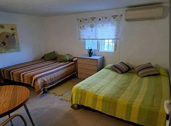 A room with two beds, a small table, and a window with a curtain.
