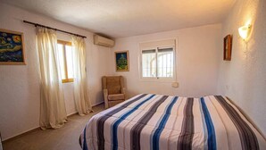 Une chambre à coucher avec un lit, une chaise, une fenêtre et un tableau accroché au mur.