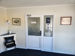 Ingresso di una camera d'albergo, con una porta recante la scritta 'Stag Park Accommodation Guests Only'. Sulla parete a destra è presente una cornice con un'immagine e, sopra la porta, un'altra cornice. Una sedia nera è posizionata a sinistra della porta.