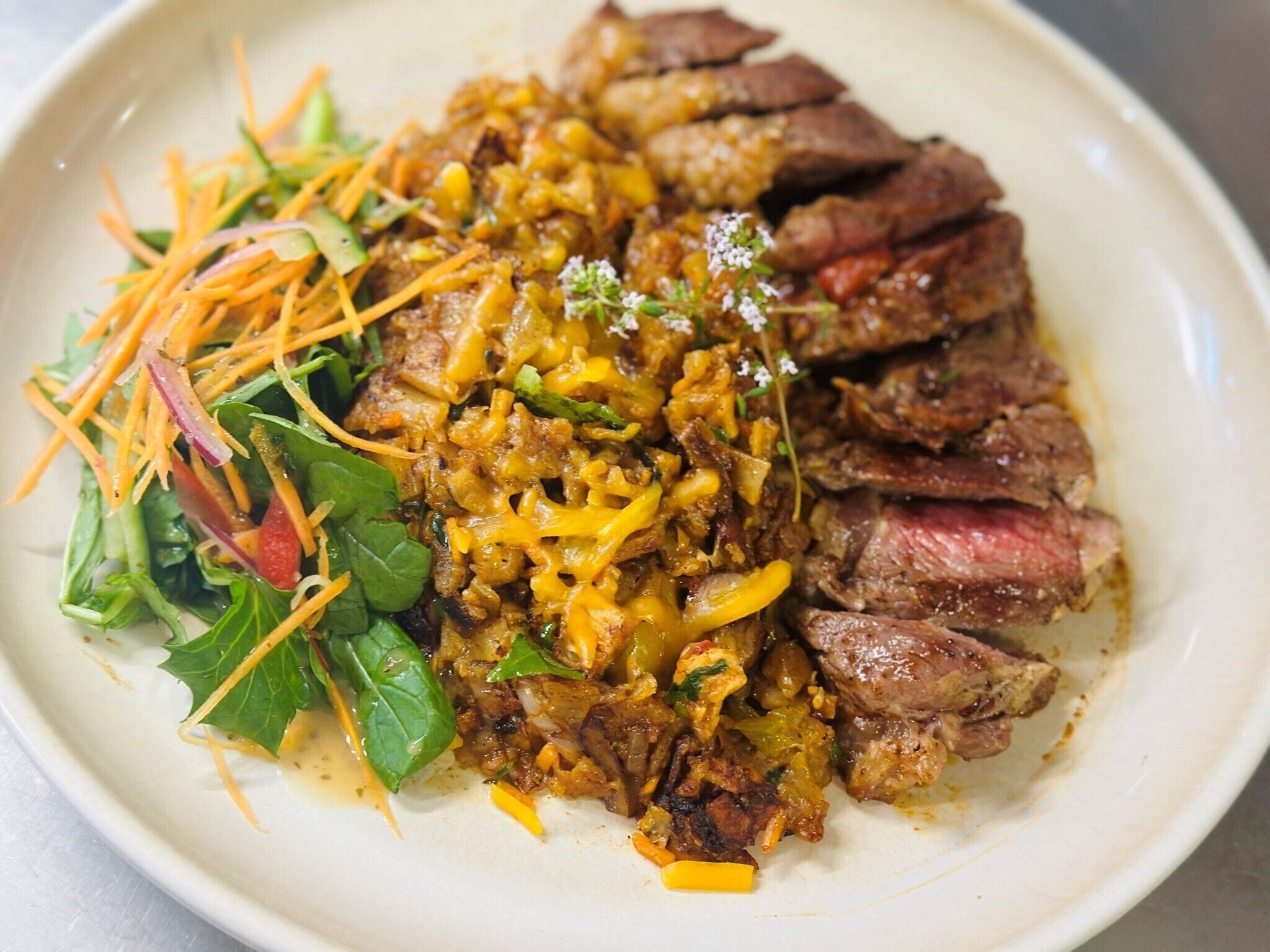 A plate with sliced steak, a vegetable medley, and a side salad.
