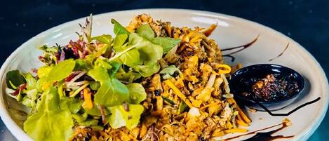 A plate of food with a side of greens and a small bowl of sauce.