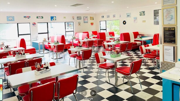 A diner with red booths and white tables, checkered floor, and various wall decorations.