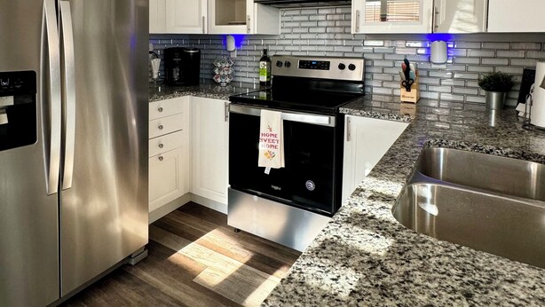 A modern kitchen with white cabinets, stainless steel appliances, a granite countertop, and a built-in oven. - Charming 3-bedroom house with WiFi, AC in serene Noblesville (Noblesville)
