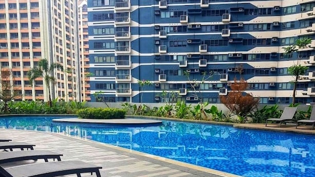 Piscina con lettini e vista su edifici alti.