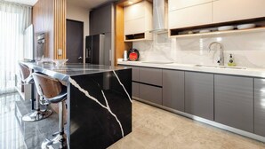 A modern kitchen with a marble island, stainless steel appliances, and a sleek design. - Departamento Punta Cero, Cintermex (Monterrey)