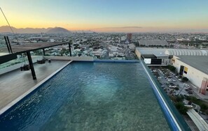 A rooftop pool with a clear view of the cityscape and mountains in the background.