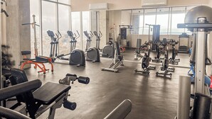 A spacious gym with various exercise equipment, large windows, and a concrete floor. - Departamento Punta Cero, Cintermex (Monterrey)