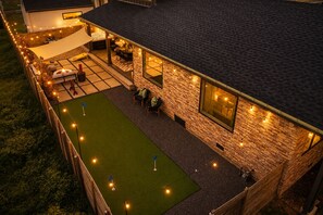 A house with a stone exterior, a covered patio, and a lawn. - Downtown Austin Luxury Stay ★ Hot Tub • Fire Pit • Minigolf (Austin)