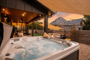 A hot tub with a wooden deck, outdoor furniture, and string lights. - Downtown Austin Luxury Stay ★ Hot Tub • Fire Pit • Minigolf (Austin)
