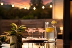 A table with four glasses and a pitcher, likely containing beverages, with a plant in the background. - Downtown Austin Luxury Stay ★ Hot Tub • Fire Pit • Minigolf (Austin)