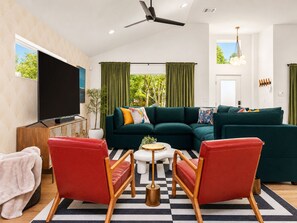 A modern living room with a sectional sofa, a flat-screen TV, and a ceiling fan. - Downtown Austin Luxury Stay ★ Hot Tub • Fire Pit • Minigolf (Austin)