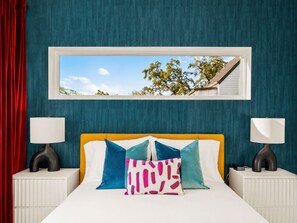 A bedroom with a bed, two bedside tables, a window, and a view of trees and a house. - Downtown Austin Luxury Stay ★ Hot Tub • Fire Pit • Minigolf (Austin)