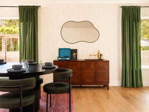 A dining area with a round table, chairs, a wooden cabinet, and a wall-mounted mirror. - Downtown Austin Luxury Stay ★ Hot Tub • Fire Pit • Minigolf (Austin)