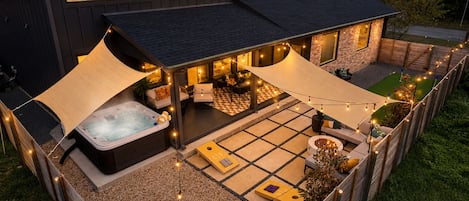 A residential property with a hot tub, outdoor seating, and string lights.