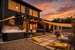 A modern outdoor patio with a hot tub, seating area, and string lights. - Downtown Austin Luxury Stay ★ Hot Tub • Fire Pit • Minigolf (Austin)