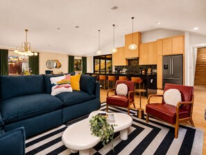 A modern living room with a sofa, armchairs, a coffee table, and a kitchen in the background. - Downtown Austin Luxury Stay ★ Hot Tub • Fire Pit • Minigolf (Austin)