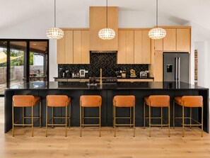A modern kitchen with a central island, bar stools, and pendant lighting. - Downtown Austin Luxury Stay ★ Hot Tub • Fire Pit • Minigolf (Austin)