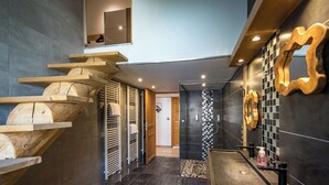Uma casa de banho moderna com chuveiro, uma prateleira de madeira e um porta-toalhas.